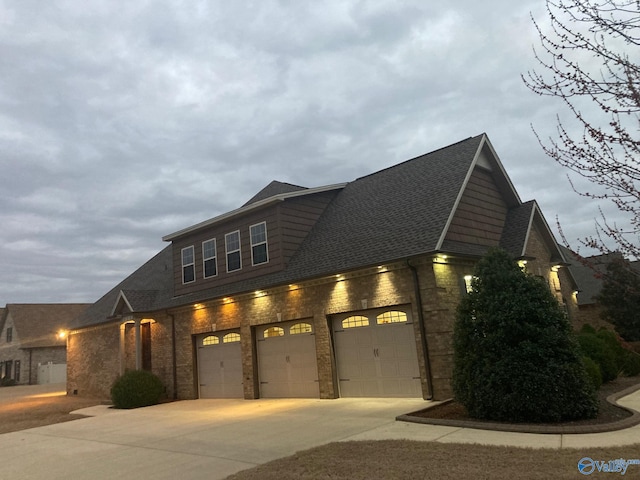 view of front facade featuring concrete driveway, brick siding, and a shingled roof