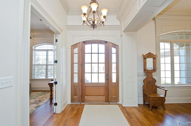 entryway with a healthy amount of sunlight, wood finished floors, and crown molding