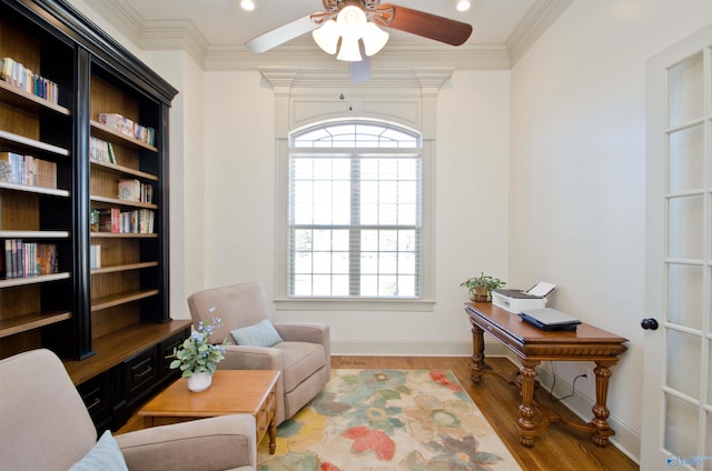 sitting room featuring a wealth of natural light, baseboards, wood finished floors, and crown molding