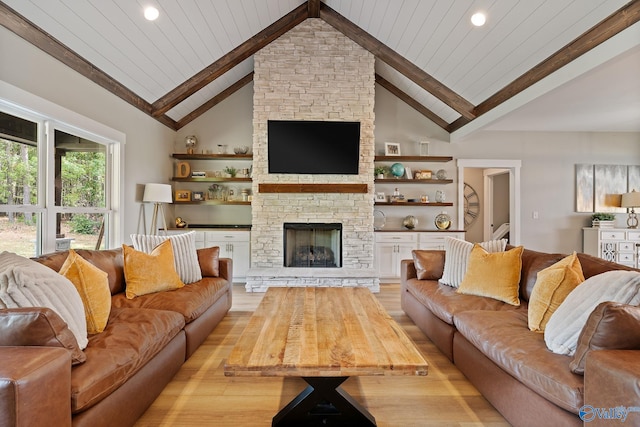 living room featuring a stone fireplace, light hardwood / wood-style flooring, beamed ceiling, and wood ceiling