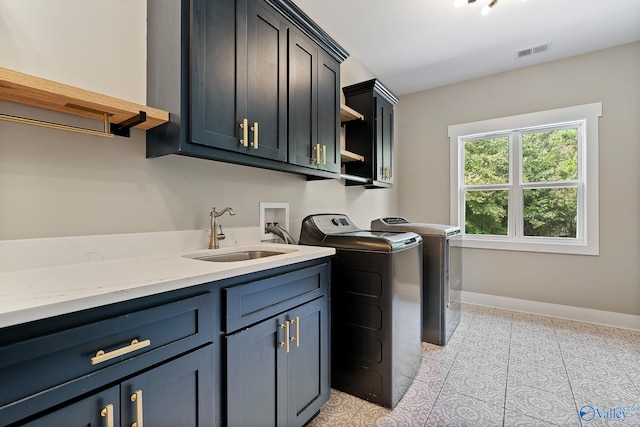 washroom featuring washing machine and dryer, sink, light tile patterned floors, and cabinets