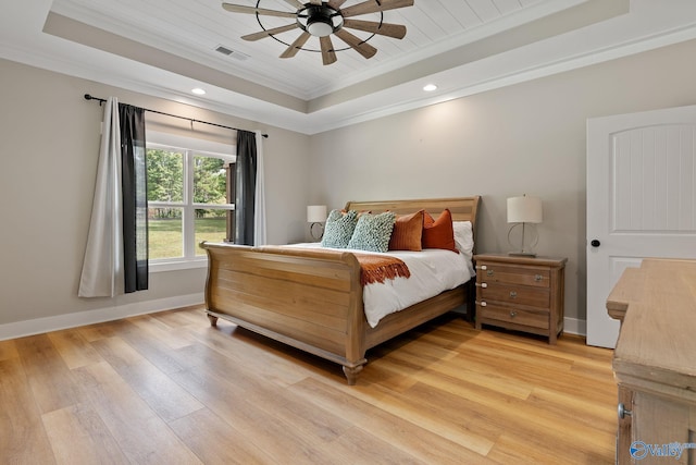 bedroom with ceiling fan, a raised ceiling, crown molding, and light hardwood / wood-style flooring