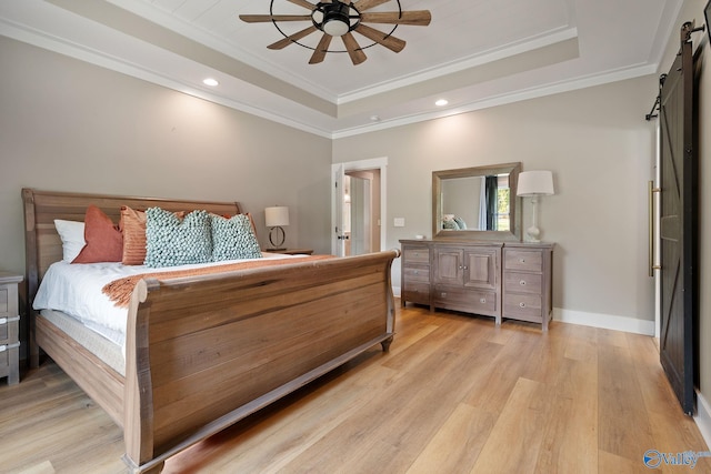 bedroom with a barn door, light hardwood / wood-style floors, ceiling fan, and crown molding