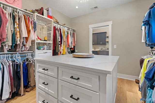 walk in closet with washer and dryer and light hardwood / wood-style floors