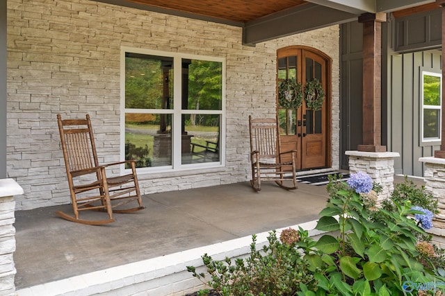 property entrance with covered porch and french doors