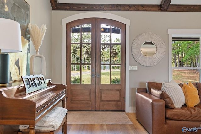 entryway featuring beamed ceiling, french doors, light wood-type flooring, and a healthy amount of sunlight