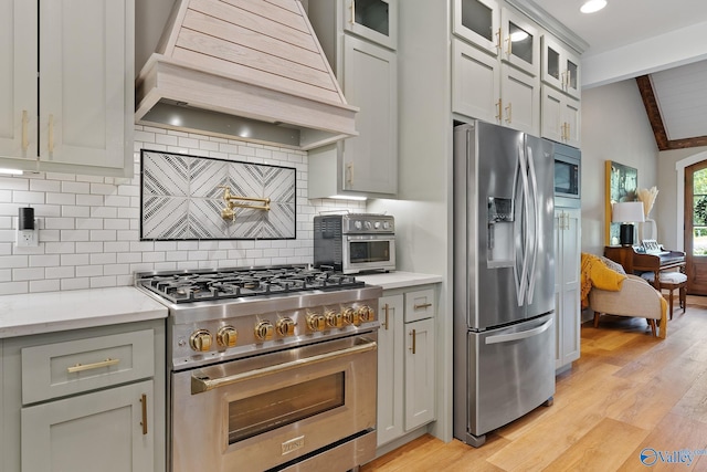 kitchen featuring premium range hood, light hardwood / wood-style flooring, vaulted ceiling with beams, tasteful backsplash, and stainless steel appliances