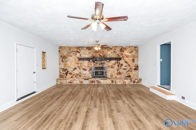 unfurnished living room featuring ceiling fan, ornamental molding, wood-type flooring, and a wood stove