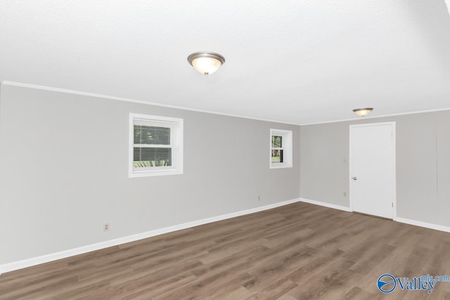 spare room featuring crown molding, dark hardwood / wood-style floors, and a textured ceiling