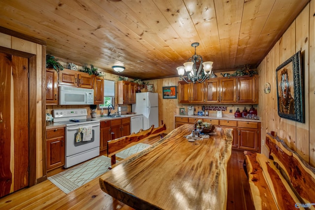 kitchen featuring wood walls, light hardwood / wood-style floors, decorative light fixtures, and white appliances