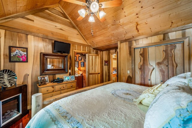 bedroom featuring a closet, ceiling fan, wooden ceiling, wooden walls, and vaulted ceiling