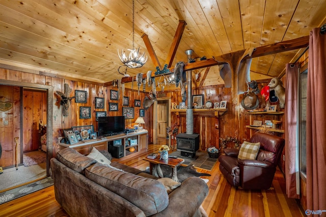 living room with a wood stove, hardwood / wood-style floors, lofted ceiling with beams, and wooden walls