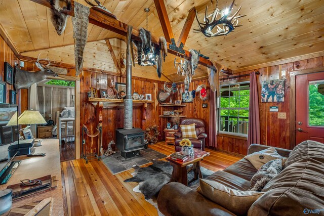 living room with hardwood / wood-style floors, a wood stove, vaulted ceiling with beams, and wooden walls