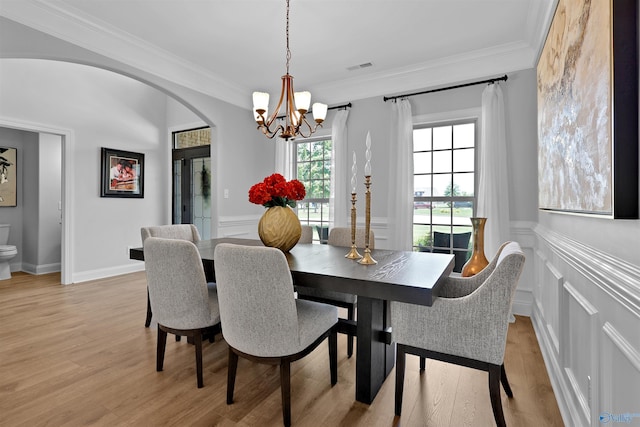 17092 Obsidian Cir, Athens, AL 35613 - dining room featuring a chandelier, arched walkways, ornamental molding, light wood finished floors, and a decorative wall