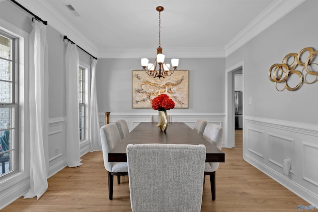 17092 Obsidian Cir, Athens, AL 35613 - dining room featuring a chandelier, ornamental molding, light wood-style flooring, wainscoting, and a decorative wall