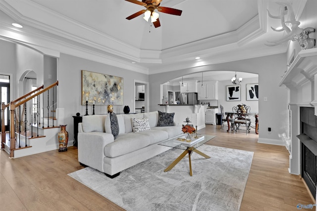 17092 Obsidian Cir, Athens, AL 35613 - living area featuring arched walkways, a ceiling fan, a fireplace, light wood-type flooring, and stairs