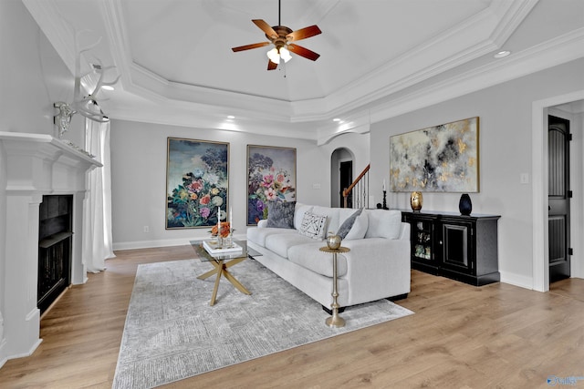 17092 Obsidian Cir, Athens, AL 35613 - living room featuring a fireplace, ceiling fan, ornamental molding, light wood finished floors, and a tray ceiling