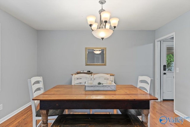 dining area featuring light wood-style floors, baseboards, and an inviting chandelier