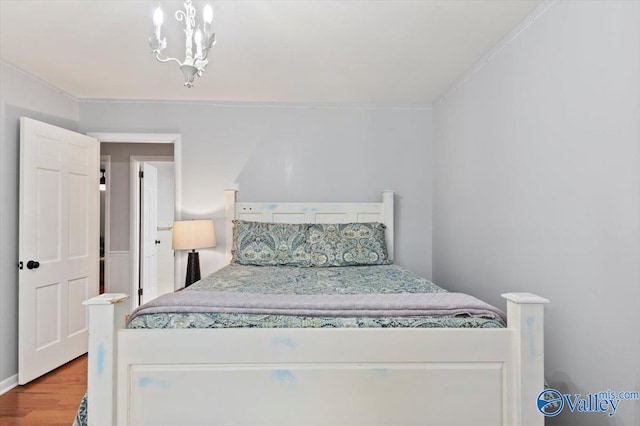 bedroom with crown molding, wood finished floors, and a chandelier
