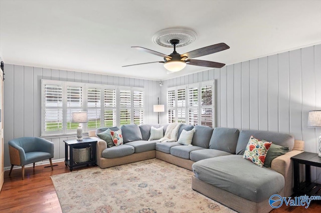 living area featuring baseboards, a ceiling fan, and wood finished floors
