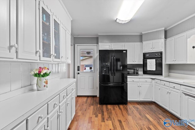 kitchen featuring light countertops, white cabinetry, ornamental molding, and black appliances