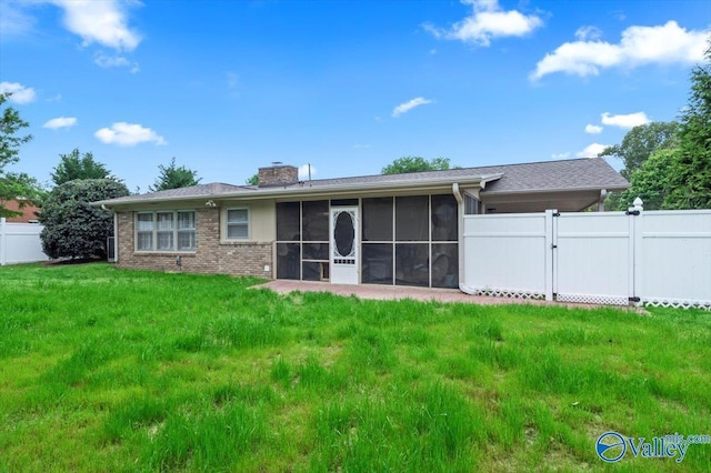 back of house featuring fence, brick siding, a sunroom, a chimney, and a lawn