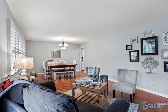 living area with an inviting chandelier, baseboards, and wood finished floors