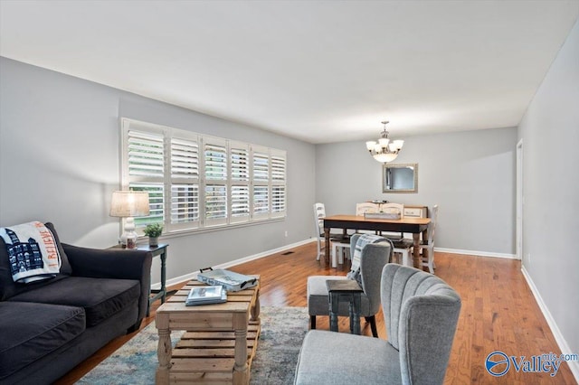 living area with baseboards, wood finished floors, and a chandelier