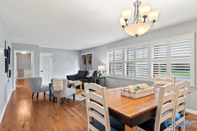dining area with baseboards, a chandelier, wood finished floors, and visible vents