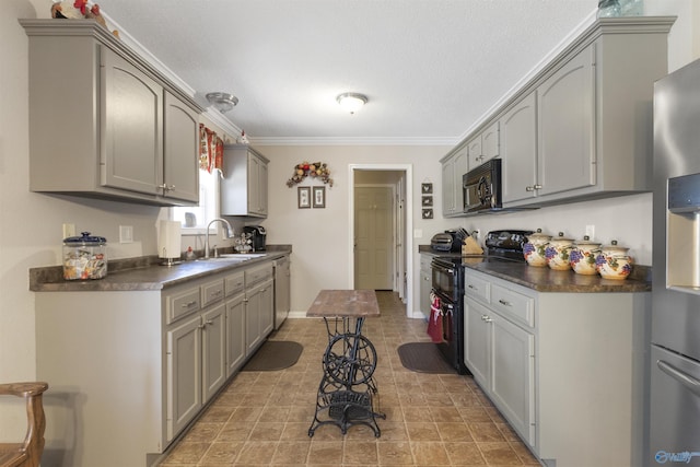 kitchen with dark countertops, black appliances, a sink, and gray cabinetry