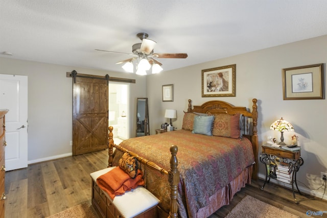 bedroom with a ceiling fan, wood finished floors, baseboards, and a barn door