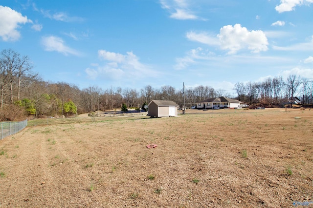 view of yard featuring a rural view, an outdoor structure, a storage shed, and fence