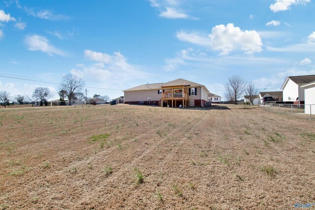 back of property with fence, a deck, and a rural view