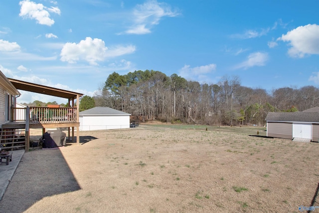 view of yard featuring stairs, a storage unit, an outbuilding, and a wooden deck