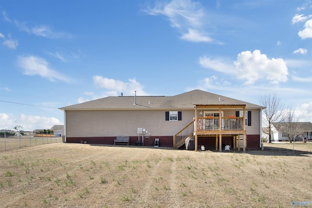 rear view of property featuring fence, a lawn, a wooden deck, and stairs