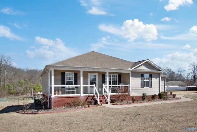 view of front of home with a shingled roof, covered porch, and fence