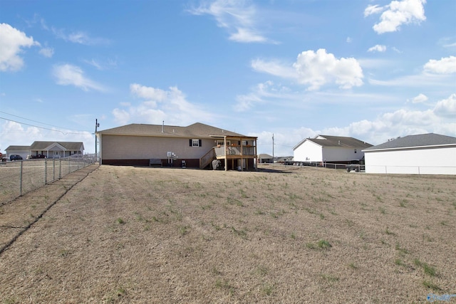 back of property with a fenced backyard, a yard, a deck, and stairs