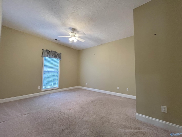 empty room featuring ceiling fan, light carpet, and a textured ceiling