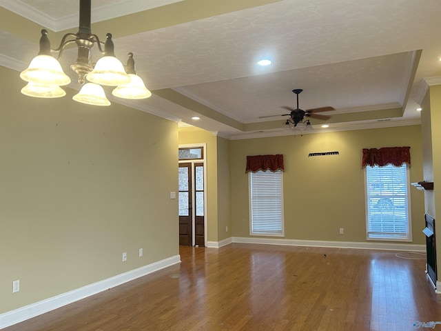 empty room with ornamental molding, a tray ceiling, dark hardwood / wood-style flooring, and ceiling fan with notable chandelier