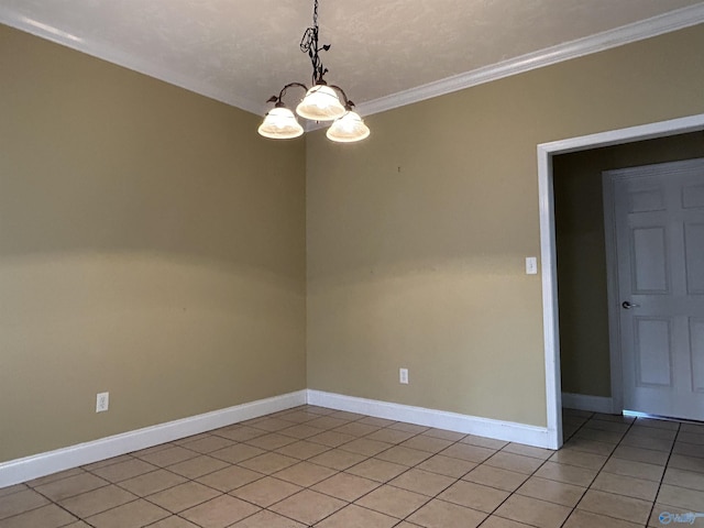 tiled spare room with ornamental molding and a chandelier