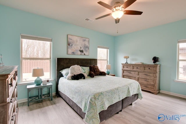 bedroom with ceiling fan, visible vents, baseboards, and light wood-style flooring