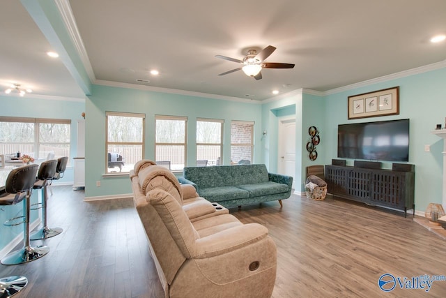 living area featuring visible vents, wood finished floors, crown molding, baseboards, and ceiling fan