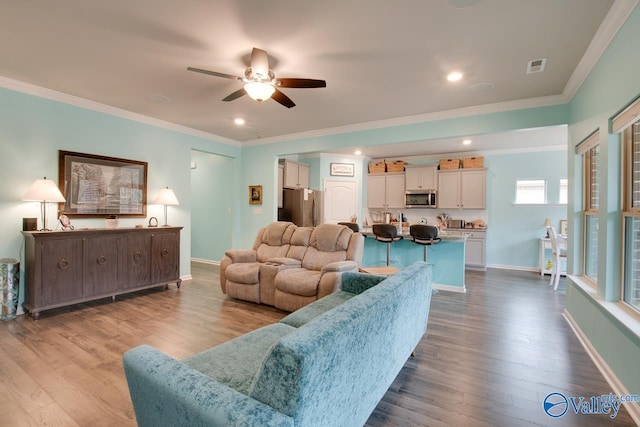 living area with baseboards, wood finished floors, ceiling fan, and ornamental molding