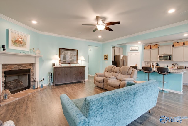 living area with light wood-style flooring, baseboards, ceiling fan, and ornamental molding