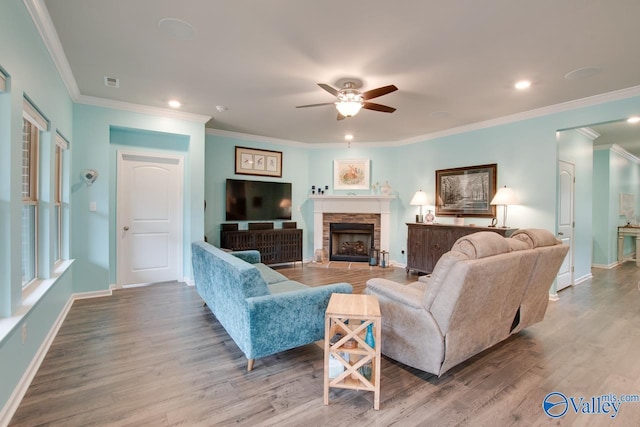 living room featuring visible vents, baseboards, a stone fireplace, wood finished floors, and a ceiling fan