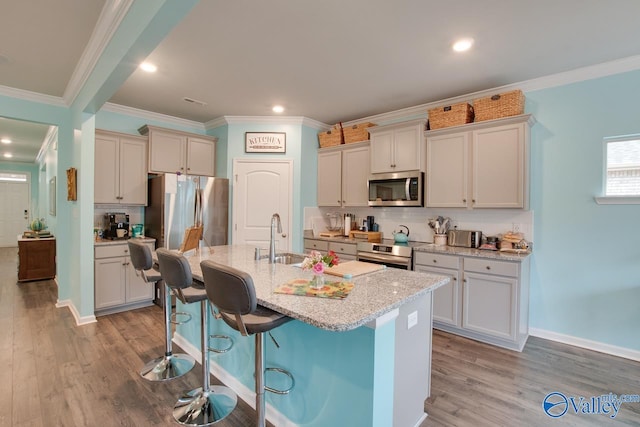 kitchen with a sink, stainless steel appliances, a kitchen bar, and light wood-type flooring