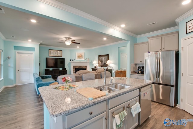 kitchen featuring open floor plan, a center island with sink, light wood-type flooring, appliances with stainless steel finishes, and a sink