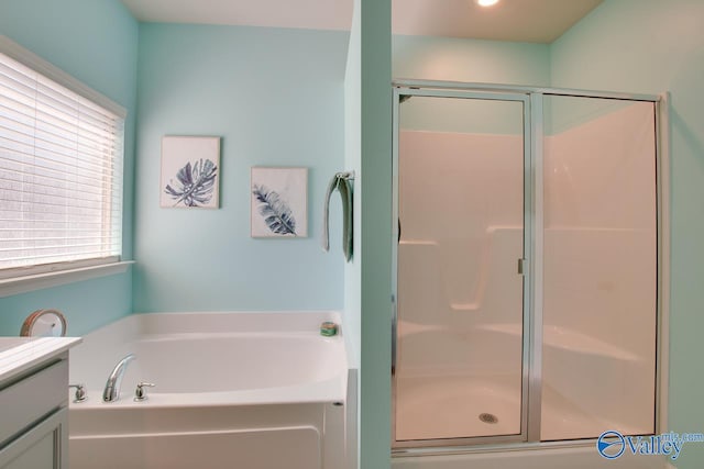 bathroom featuring vanity, a shower stall, and a garden tub