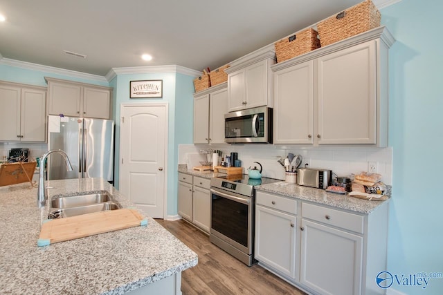 kitchen with decorative backsplash, ornamental molding, appliances with stainless steel finishes, and a sink