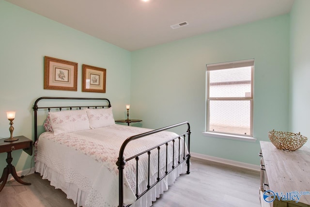 bedroom with visible vents, light wood-type flooring, and baseboards